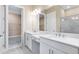 Bright bathroom featuring double vanity with white cabinets, quartz countertops, and a glass shower at 7661 Moonbeam Ave, Sarasota, FL 34241