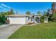 One-story home with gray exterior, a two-car garage, and a landscaped yard at 3523 Whitman St, North Port, FL 34288