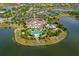Aerial view of a clubhouse situated on a peninsula between two lakes, featuring multiple pools, tennis courts, and lush landscaping at 7928 Matera Ct, Lakewood Ranch, FL 34202