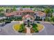 Aerial showcases the grand clubhouse with lush landscaping and circular driveway with flowering bushes at 7928 Matera Ct, Lakewood Ranch, FL 34202