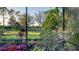 View of the lush, meticulously landscaped backyard through the screen, showing beautiful flowers and trees at 7928 Matera Ct, Lakewood Ranch, FL 34202