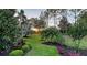 Lush backyard with well-manicured lawn, flower beds, mature trees, and vibrant greenery at 7928 Matera Ct, Lakewood Ranch, FL 34202