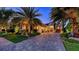 Stunning exterior showcasing lush landscaping, large palms, and a paver driveway leading to a well-lit home at 7928 Matera Ct, Lakewood Ranch, FL 34202