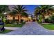 Beautiful home exterior at dusk highlighting the long paver driveway, professional landscaping, and illuminated palms at 7928 Matera Ct, Lakewood Ranch, FL 34202
