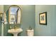 Charming powder room with a decorative mirror, sleek fixtures, and calming teal walls at 7928 Matera Ct, Lakewood Ranch, FL 34202