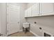 Laundry room with white cabinets, utility sink, and tile floor at 12221 Perennial Pl, Bradenton, FL 34211