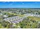 An aerial neighborhood view showcasing lush trees surrounding residential homes, with clear blue skies overhead at 1782 White Orchid Ct, Sarasota, FL 34235