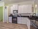 White kitchen with black appliances, granite countertops, and light flooring at 4139 63Rd E Ter, Sarasota, FL 34243