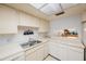 Galley kitchen with white cabinets, a double sink, and a pass-through window at 6435 Egret Ln # 409, Bradenton, FL 34210