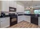 Modern kitchen featuring white cabinets, black appliances, and wood-look flooring at 4139 63Rd E Ter, Sarasota, FL 34243