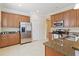 A bright kitchen with stainless steel refrigerator, granite countertops, and wood cabinets at 115 Winding River Trl, Bradenton, FL 34212