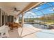 Covered patio area with ceiling fan that overlooks a sparkling screened pool, spa, and a tranquil lake at 115 Winding River Trl, Bradenton, FL 34212