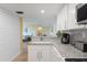 Modern kitchen featuring white cabinetry, granite countertops, and a view into the living area at 3006 Caring Way # 224, Port Charlotte, FL 33952