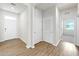 Hallway with wood-look flooring, white doors, and neutral walls, offering a view into an adjacent room at 3718 Mossy Limb Ct, Palmetto, FL 34221