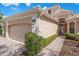 Exterior angle of a beige home showcasing brick pavers leading to an arched doorway and three car garage at 650 Crane Prairie Way, Osprey, FL 34229