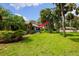 Backyard patio with blue couch and red umbrella, lush landscaping at 7547 Silver Fern Blvd # 54, Sarasota, FL 34241