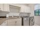 Convenient laundry room with ample cabinetry, a sink, and modern washer/dryer at 9291 Swaying Branch Rd, Sarasota, FL 34241