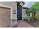 Close-up of the front door featuring stylish stonework, an elegant entry, and lush, tropical landscaping at 6547 Willowshire Way, Bradenton, FL 34212