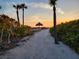 Path to beach at sunset with thatch umbrellas at 1241 Gulf Of Mexico Dr # 708, Longboat Key, FL 34228