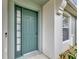 A close up of the beautiful blue-green front door with sidelight, adding curb appeal at 10444 48Th E Ct, Parrish, FL 34219