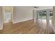 Bright living room with wood-look floors, neutral walls, ceiling fan, and sliding glass doors to the outside at 10444 48Th E Ct, Parrish, FL 34219