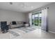 Spacious living room with grey sectional sofa and sliding glass doors leading to patio at 11655 Bluestone Ct, Parrish, FL 34219