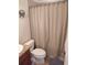 Bathroom with beige shower curtain, toilet and tiled floor at 11776 Angler'S Club Dr, Placida, FL 33946