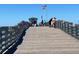 Picturesque fishing pier featuring wooden planks, railings, and ocean views under a clear blue sky at 2005 Tocobaga Ln, Nokomis, FL 34275