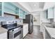 Modern kitchen features stainless steel range and refrigerator, and light teal cabinetry at 2420 Sunnyside St, Sarasota, FL 34239