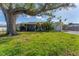 Single story home with large tree and well-maintained lawn at 2420 Sunnyside St, Sarasota, FL 34239
