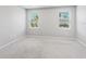 Bright bedroom with neutral carpet, gray walls, and two windows offering natural light at 5719 Woodland Sage Dr, Sarasota, FL 34238
