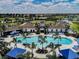 Aerial view of community pool featuring blue umbrellas, lounge chairs, and palm trees at 5719 Woodland Sage Dr, Sarasota, FL 34238