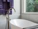 Close-up of a soaking tub with a stylish faucet and elegant marble tile surround at 7317 Crape Myrtle Way, Sarasota, FL 34241