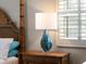 Bedroom nightstand featuring a decorative lamp with shuttered windows in the background at 7317 Crape Myrtle Way, Sarasota, FL 34241