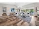 Bright living room featuring wood-style tile floors, modern furnishings, and sliding glass doors to the outdoor living space at 7317 Crape Myrtle Way, Sarasota, FL 34241