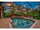 Evening view of a luxurious screened pool and spa with fire pit at 854 Macewen Dr, Osprey, FL 34229