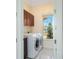 Bright laundry room with front load washer/dryer, storage cabinets and natural light from the window at 1900 Colleen St, Sarasota, FL 34231