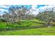 Horse paddock with lush grass, mature trees and black fence at 29205 Saddlebag Trl, Myakka City, FL 34251