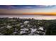 Sunset aerial view of waterfront estate featuring a private boat dock, pool, and lush tropical landscaping at 1243 Starboard Ln, Sarasota, FL 34242