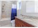 Bathroom with a shower-tub combo featuring a blue curtain and a wood vanity topped with a stone countertop at 1243 Starboard Ln, Sarasota, FL 34242