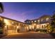 A well-lit, two-story home boasting an attached three car garage and a brick paved drive way at twilight at 1243 Starboard Ln, Sarasota, FL 34242