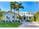 A well maintained two-story home with a metal roof, front porch and a brick paved drive way surrounded by palm trees at 1243 Starboard Ln, Sarasota, FL 34242