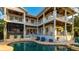An expansive multi-level outdoor living space with a pool, spa, covered balcony, lounge seating, and tropical plants at 1243 Starboard Ln, Sarasota, FL 34242