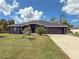 Single-story home with gray exterior, two-car garage, and lush landscaping at 1661 Atwater Dr, North Port, FL 34288
