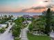 Sunset aerial view of the home with lush landscaping, an extended driveway, and a view of the ocean at 5861 Gulf Of Mexico Dr, Longboat Key, FL 34228