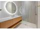 Modern bathroom with illuminated round mirror, floating vanity, and glass enclosed shower at 5861 Gulf Of Mexico Dr, Longboat Key, FL 34228