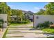 Long driveway with modern pavers leads to a well-landscaped home and gated entrance at 5861 Gulf Of Mexico Dr, Longboat Key, FL 34228