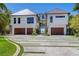 A modern, two-story home with a lush lawn, a three-car garage, and a walkway to the beach at 5861 Gulf Of Mexico Dr, Longboat Key, FL 34228