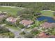 Aerial view showcasing a home near a pond and golf course, lush landscaping, and barrel tile roof at 10209 Discovery Ter, Bradenton, FL 34212