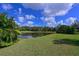 Scenic backyard view showcasing a tranquil pond reflecting the blue sky, bordered by lush greenery and mature trees at 10209 Discovery Ter, Bradenton, FL 34212